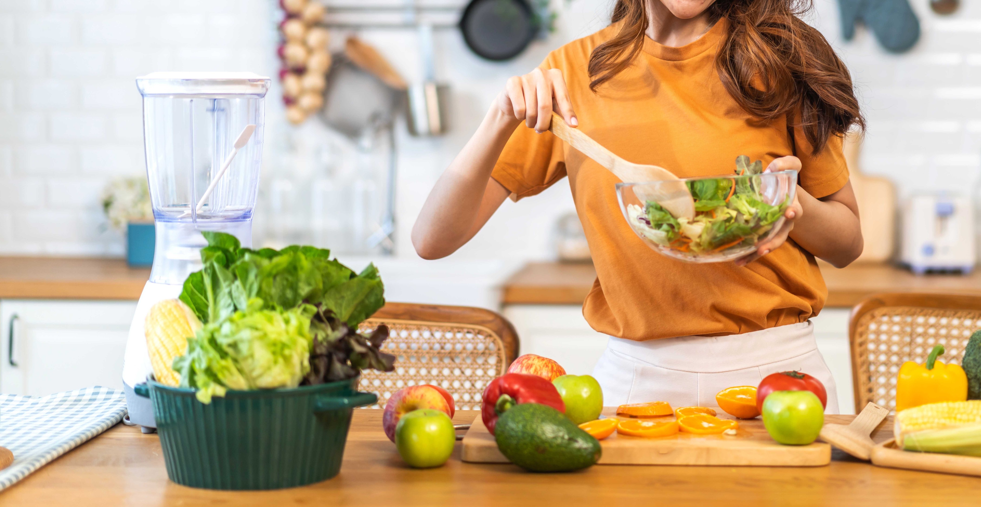 Woman enjoying a fresh vegetable salad in her kitchen.